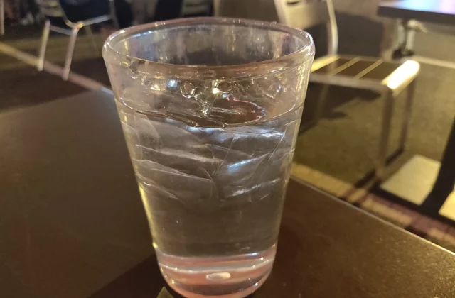 Стакан воды с мелкими пузырьками газа на стенках на кухонном столе